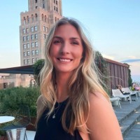 A photo of Elizabeth in front of a building with a blue sky in the background.